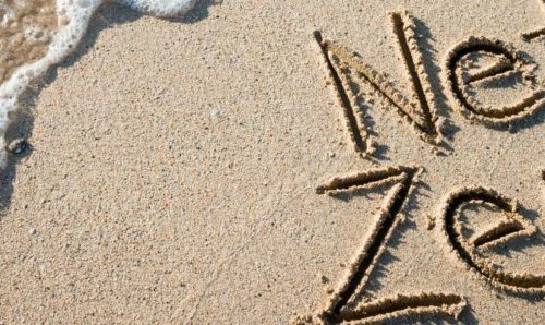 'Net zero' written in the sand on a beach
