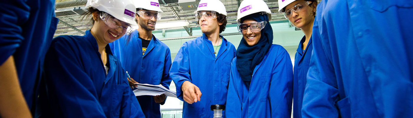 chemical engineering students in hard hats and blue lab coats