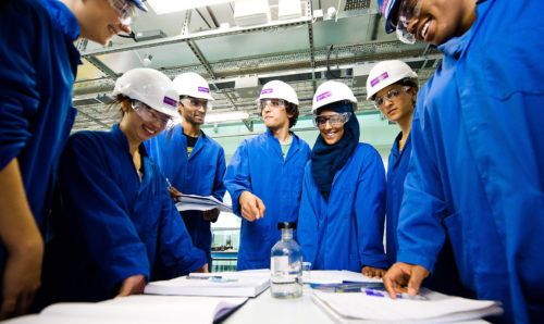 chemical engineering students in hard hats and blue lab coats