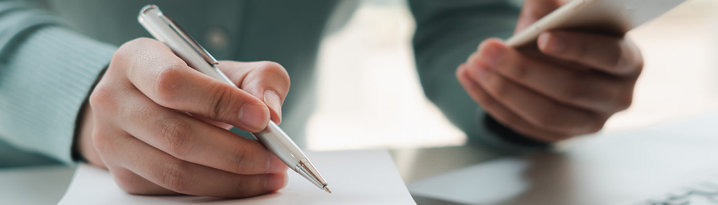 Man checking phone and writing notes