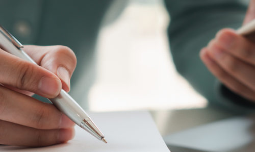 Man checking phone and writing notes