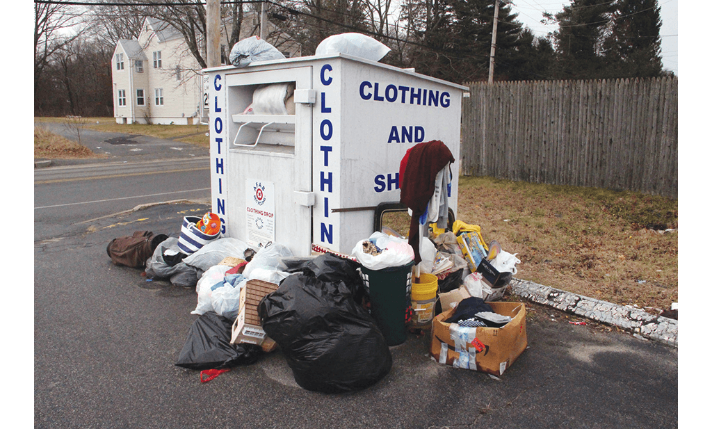 Photo of a clothing bank with multiple waste items piled up around it in bin bag.