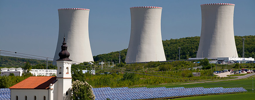 The water-cooling towers of the Mochovce nuclear power station in the Slovak Republic. A solar farm and a small church are in the foreground.