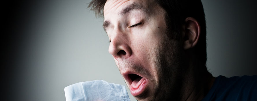 A man sneezing into a hanky