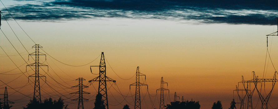 A sunrise behind a line of high voltage towers or pylons
