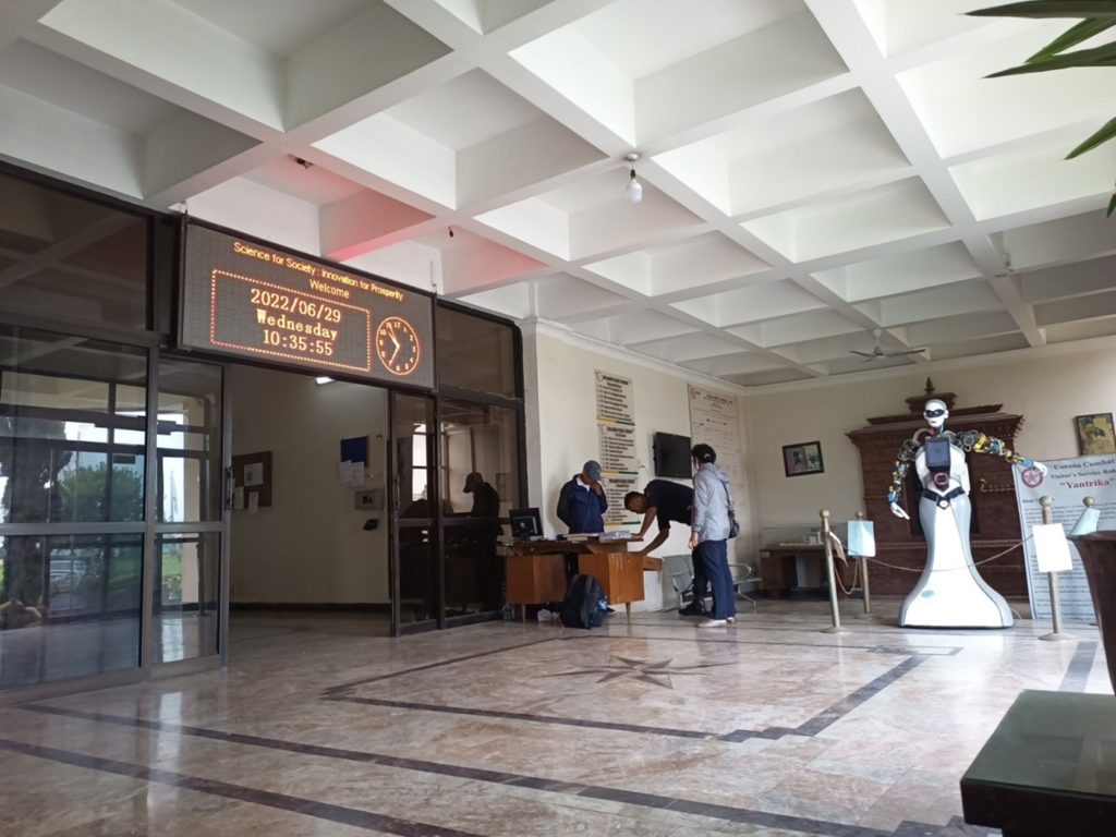 A wide entrance way with blocked ceiling. A tall figured humanoid robot stands near the entrance