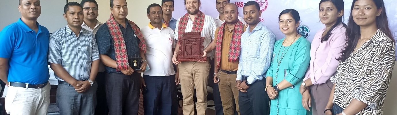 A group of people with Giles at the centre holding a Nepalese Khata.