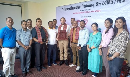 A group of people with Giles at the centre holding a Nepalese Khata.