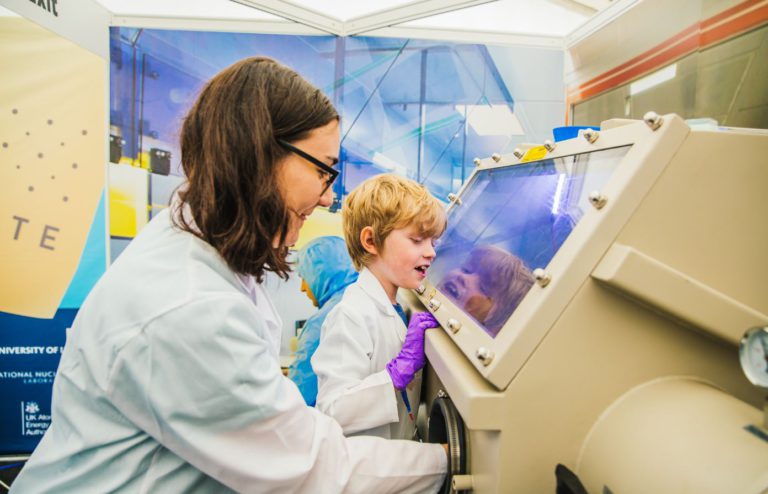 Child looking at glove box with woman scientist