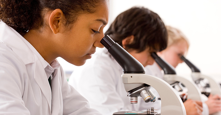 Three young scientists using microscopes