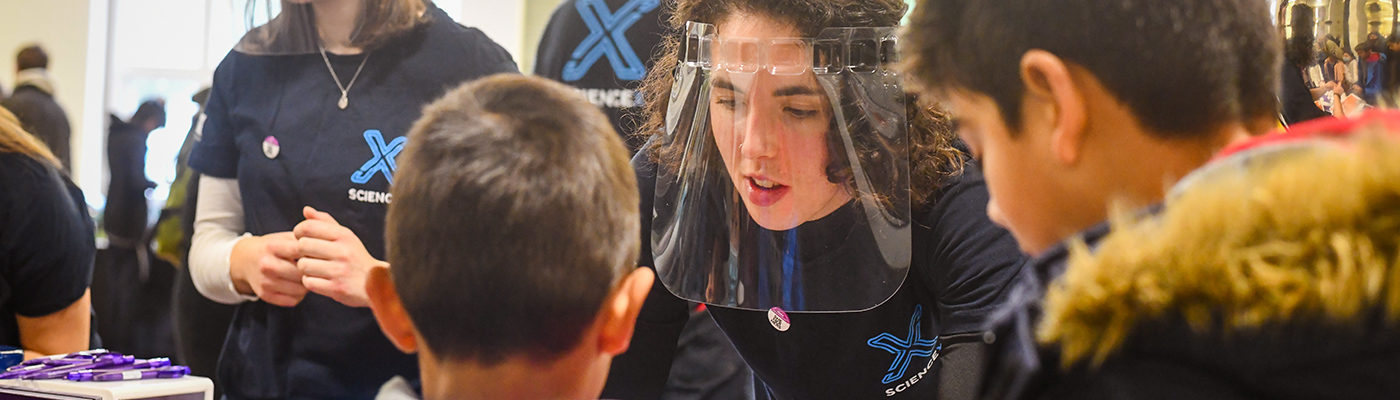 ScienceX volunteer speaks to children visitors