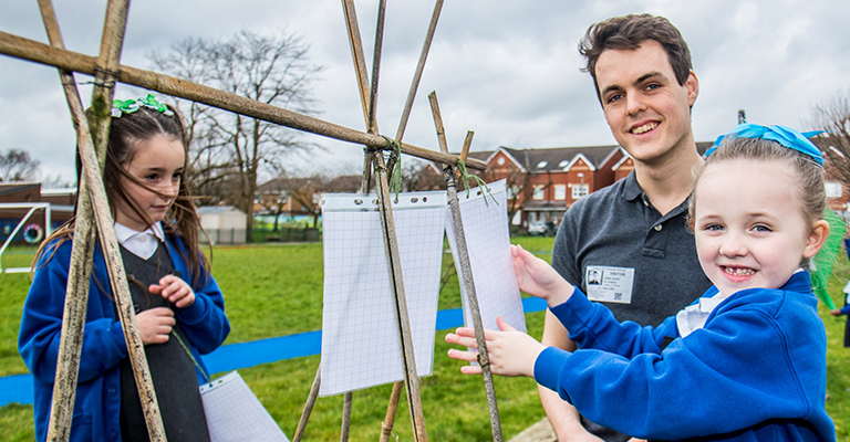 Link scientist Dan Blight and pupils hang up sheets of paper.