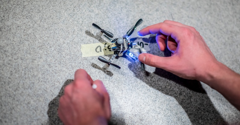 A pair of hands manoeuvre a small flying robot.