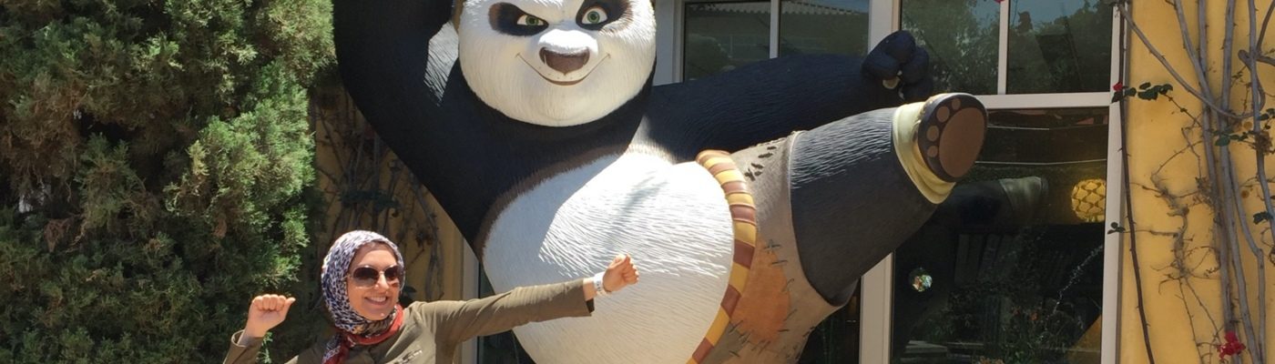 Dr Zahra Montazeri doing a kung fu kick in front of a large Kung Fu Panda statue.