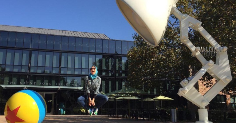 Dr Zahra Montazeri leaps into the air next to a large Pixar lamp and ball.