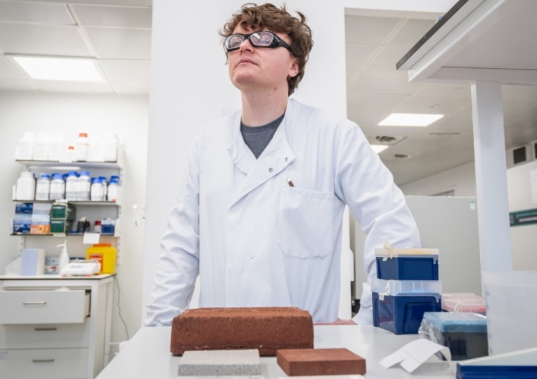 Dr Aled Roberts stands behind different brick samples.