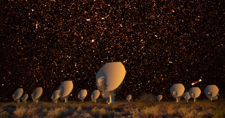 MeerKAT radio telescope array lined up with many stars in the night sky behind.