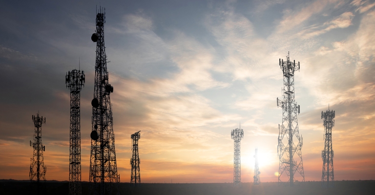 Antenna telephone and communication towers with a sunset background.