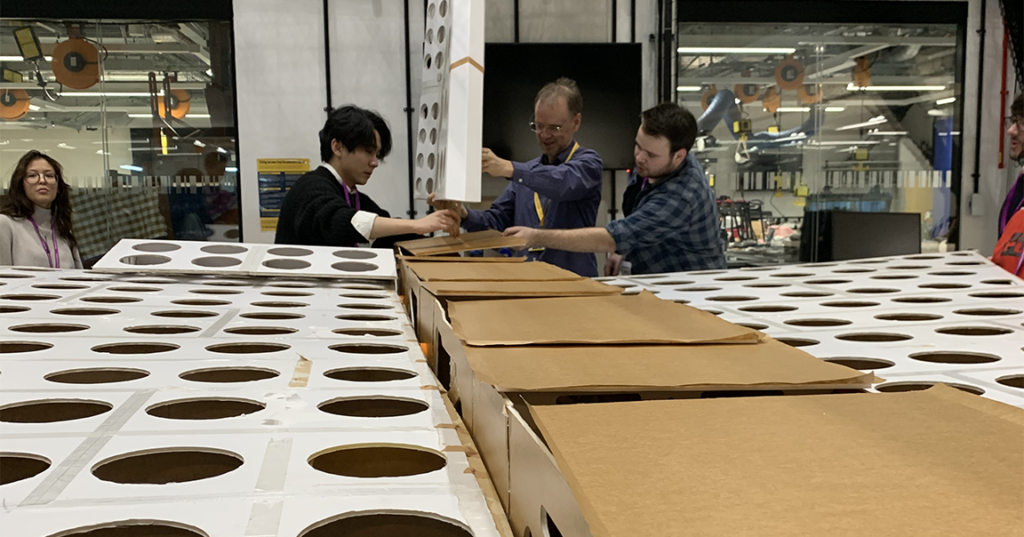 An academic assisting students with the construction of a giant foamboard aircraft 