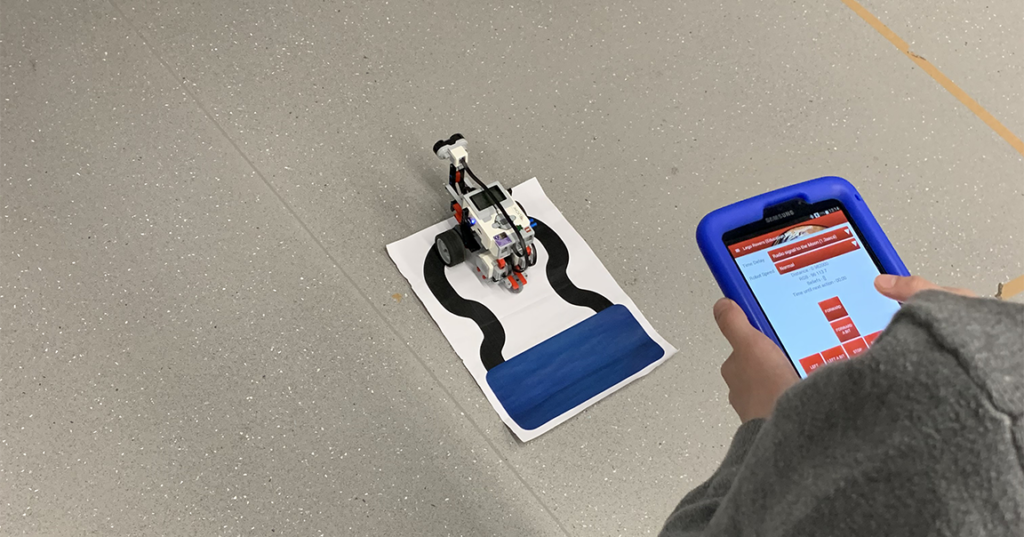 A robot on the ground being controlled by an iPad 