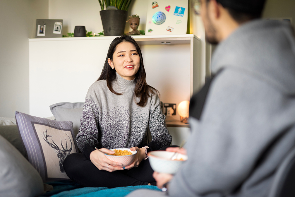 Two students chatting over bowls of cereal.