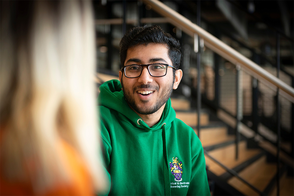 A student wearing glasses and a green hoodie.
