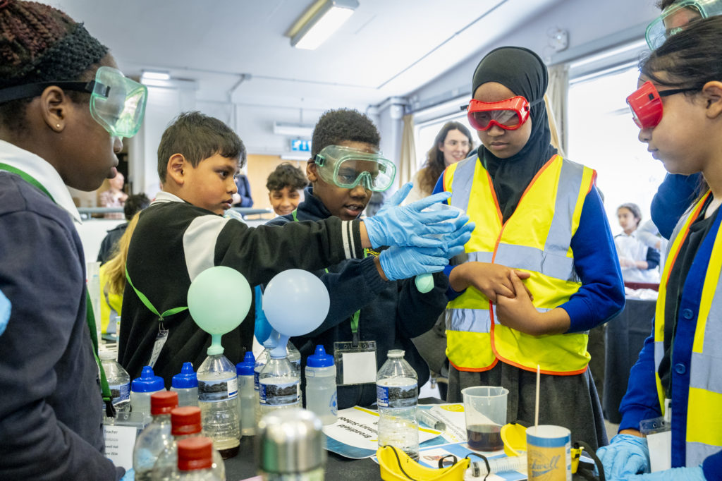A group of kids wearing safety goggles and gloves
