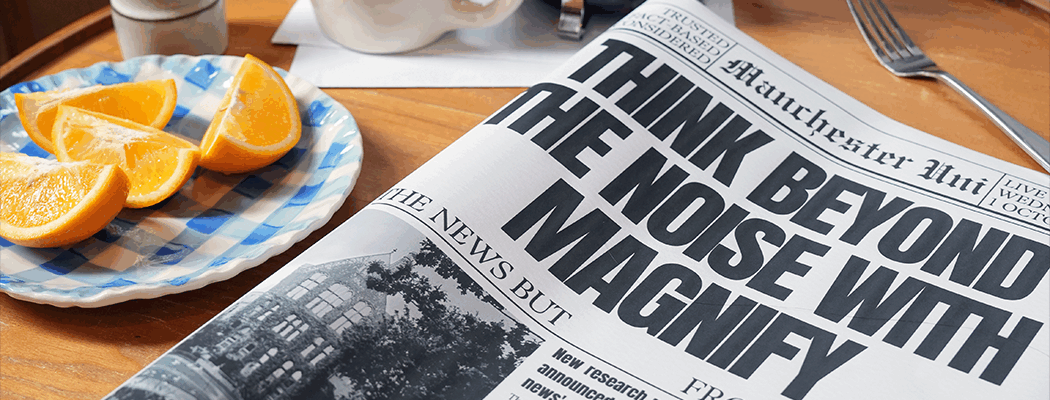 A plate of sliced oranges sits beside a newspaper reading 'Think beyond the noise with Magnify'