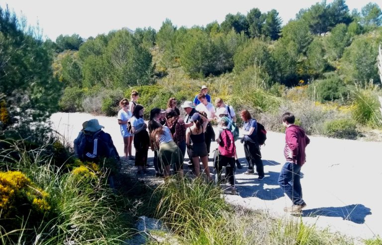 Students standing outside on a track in the countryside in a group.