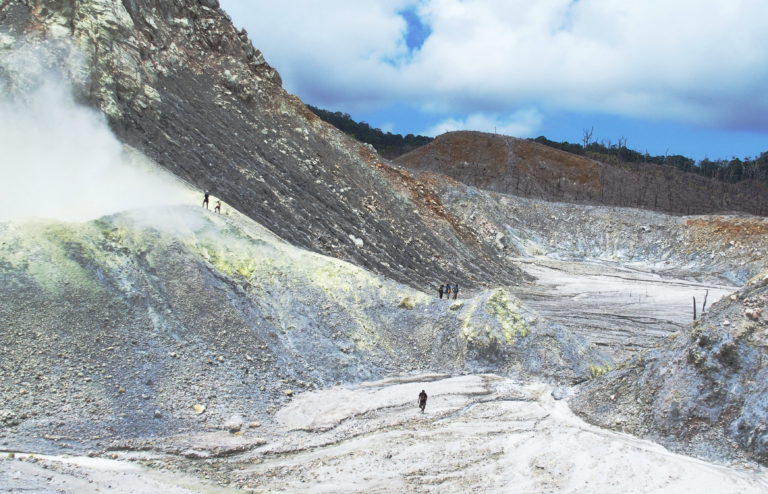 Side of a volcano and people walking on it.