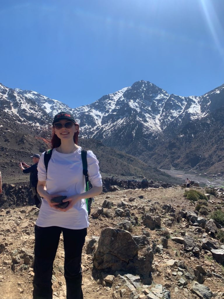 Ayesha smiling whilst holding camera on an earth science field trip.