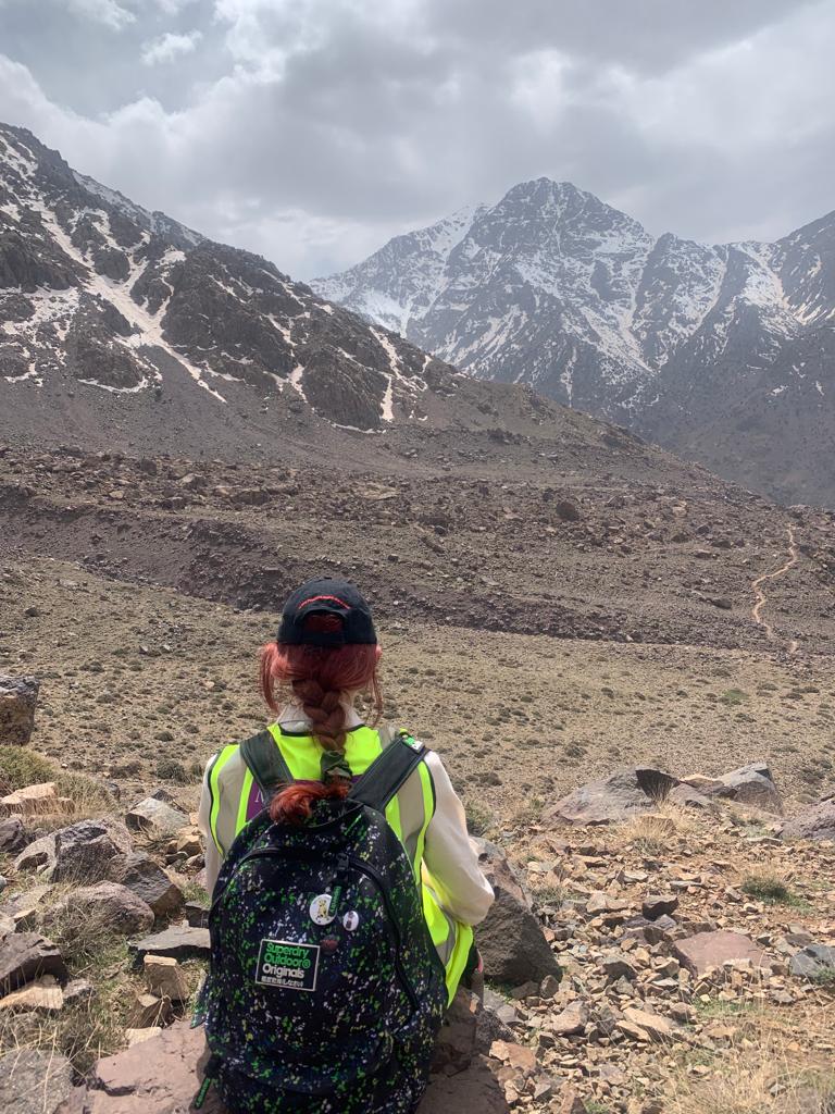 Ayesha in a high vis looking out at mountains on an earth science field trip.
