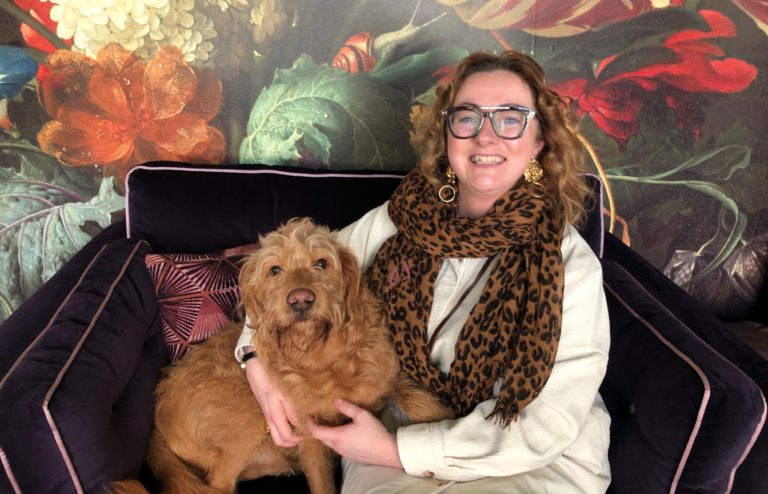 Lesley-Ann sits on a sofa with her dog Syd.