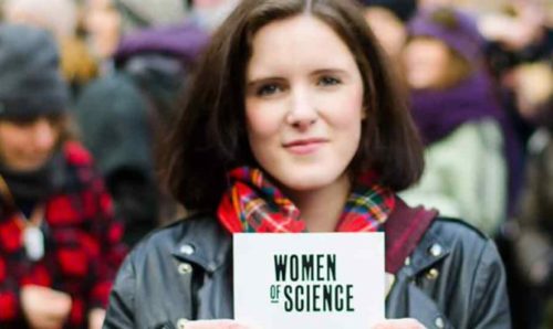 Woman holding up card that reads 'Women of Science'.